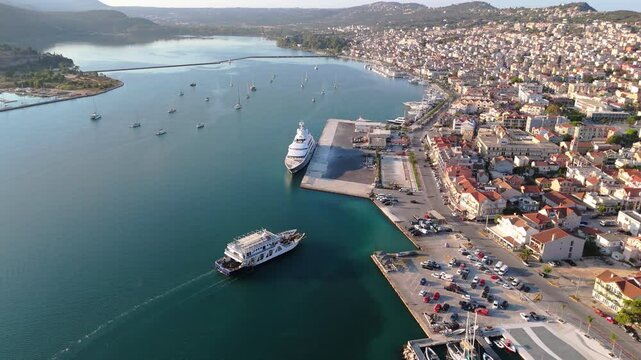 Drone orbit around ferry approaching Argostoli, Kefalonia, Greece, the port, waterfront, and surrounding mountains