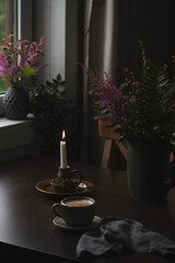 table with coffee and candles in dark rustic country cottage. Slow living.