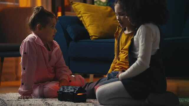 Three girl friends telling spooky stories and having fun during sleepover party