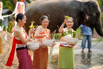 Group of beautiful Thai women in the Thai traditional dress playing to sprinkle water on the Thai...