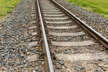 Single, diagonal railroad track through countryside landscape with a grass field. Empty railway...