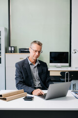 Professional businessman working at office with laptop, tablet, and notes. Perfect for business, finance, accounting