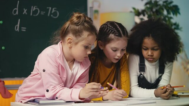 Three focused girls working on a math task together in class, finding a solution