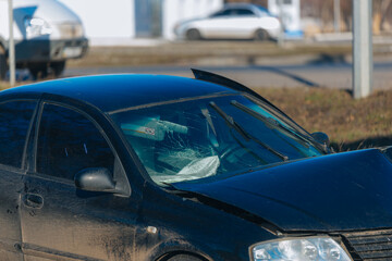 Car after an accident on the side of the road, close-up. A black car with serious damage to the front end is at the scene of an accident. Car after an accident on the side of the road. Accident