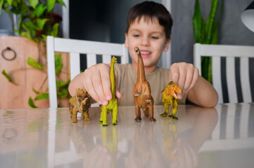 Toddler boy 6 y.o. playing with dinosaurs at home. Boy learning paleontology by dino toys at leisure. Concept of clever child and early education. Evolution and paleontology game for young kid.