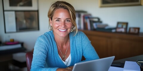 A smiling woman sits confidently at her desk, engaged with her laptop, embodying success and inspiration in a professional setting.