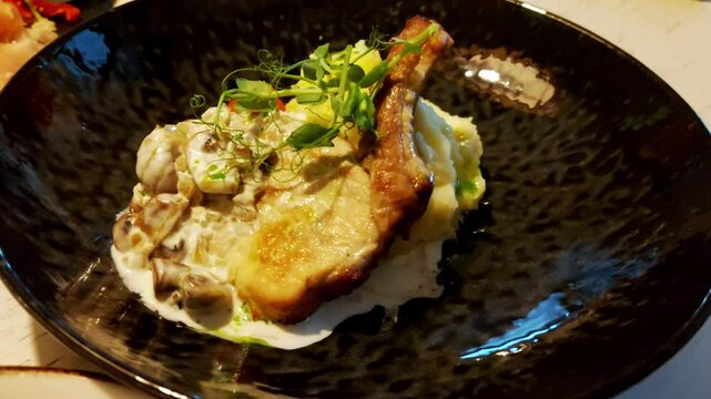 Pork meat on the bone with mashed potatoes, garlic sauce and herbs, close-up, appetizing