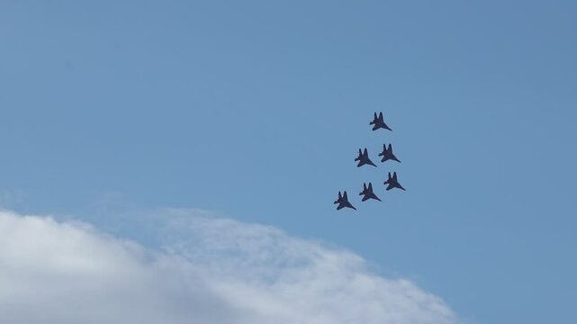 Military jets formation flying changing shape in cloudy sky