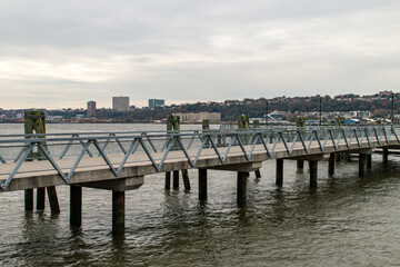 Muelle que conduce al restaurante The Baylander, un antiguo barco de guerra de la época de Vietnam, New York, USA. Río Hudson al atardecer en un día nublado de otoño al fondo New Jersey.