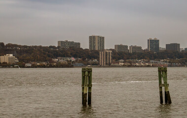 Pilones de madera en el río Hudson y New Jersey al fondo. Río Hudson al atardecer en un día nublado de otoño desde Nueva York.