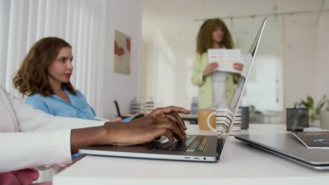 Close-up shot of businesswoman typing on laptop while sitting at table at meeting