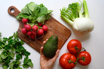 Hands preparing healthy food or salad. Fresh vegetables and herbs on the table. 