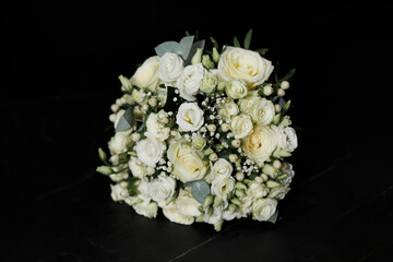 A bouquet of white roses and other small white flowers such as gypsophila. The bouquet also contains small white berries and green leaves. 