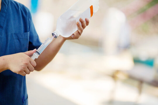 Closeup veterinarian is using saline in a syringe to wash out the inflamed eyes of a sick elephant in the elephant hospital.