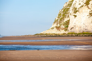 An absolutely breathtaking view of a tranquil beach and majestic towering cliffs beneath a clear...