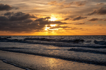 An absolutely breathtaking sunset is illuminating the gentle ocean waves, creating a truly peaceful coastal atmosphere