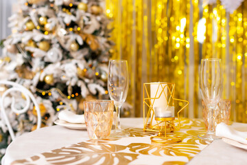 New Year's table setting in a photo studio. Plates with glasses on a Christmas tablecloth