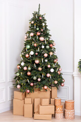 Christmas tree with white and pink toys on a light wall. New Year's decoration in a photo studio