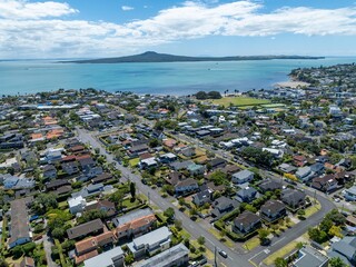 Aerial view of a residential neighborhood near the ocean, showcasing diverse housing styles....