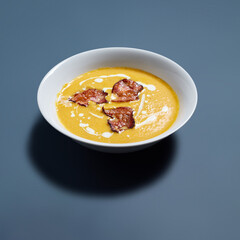Creamy Pumpkin Soup with Crispy Bacon in White Bowl Against Blue Background