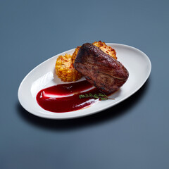 Grilled Steak with Corn and Red Sauce on White Plate Against Blue Background
