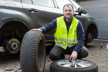 A man performs seasonal tire changes and prepares a car for winter or summer, demonstrating care in...