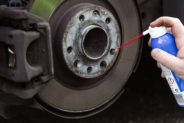 Thread spray. A man applies a special lubricant to threads before installing a wheel.