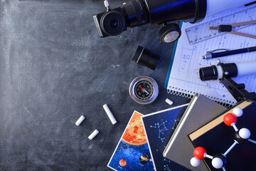 Material books and telescope for study of astronomy on blackboard