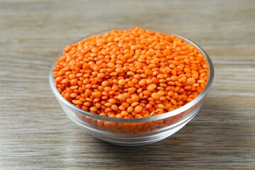 Red lentils in a bowl on wooden background 