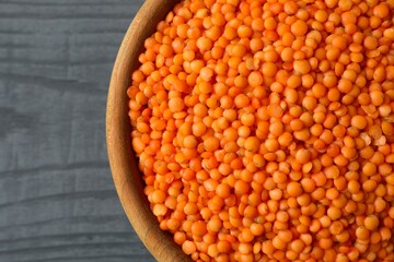 Red lentils in a bowl on wooden background 
