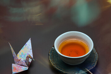 和柄の折り紙で作られた折り鶴と、茶托に乗せられたほうじ茶