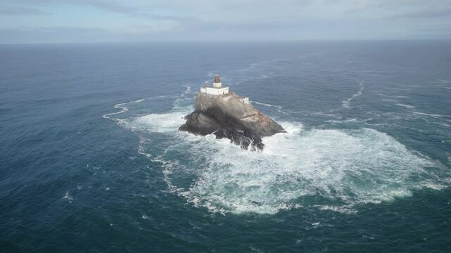Pull out drone shot of Tillamook Rock Light lighthouse with waves crashing during the day in North Pacific Ocean, northern Oregon Coast, USA