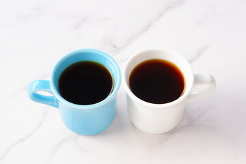 淹れたてのコーヒーが入ったふたつのマグカップで、ふたりがコーヒーを飲みながら、打ち合わせをしているイメージ
