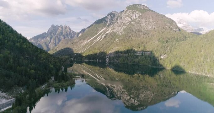 Aerial drone view of Lago del Predil in Tarvisio. Panoramic from above with the view of the Alps in background, trekking and summer holidays. Perfect reflection on the surface creates a human face.
