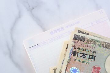 テーブルの上に開いた状態で置かれた銀行の預金通帳と、1万円札
