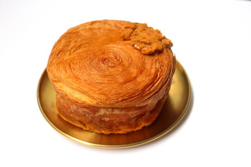 Croissant roll or timbering on yellow metal round dish on white background.