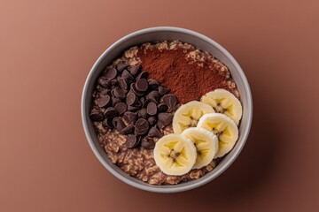 Fototapeta premium Delicious bowl filled with oatmeal, banana slices, cocoa powder,