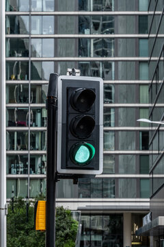 Green traffic light mounted on a pole in front of a contemporary office building.