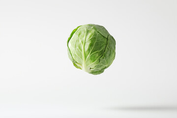 Fototapeta premium Fresh and vibrant green Brussels sprout floating against clean white background, showcasing its round shape and textured leaves, perfect for healthy cooking