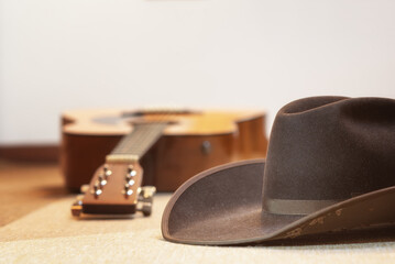 brown cowboy hat and acoustic guitar out of focus in background - country music and line dance - text space on top