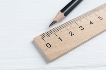Ruler and pencil on white wooden table, closeup