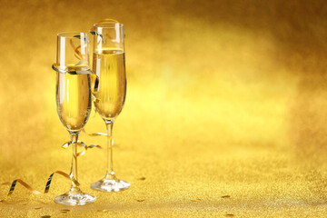 Champagne in glasses, confetti and streamers on golden background. Space for text