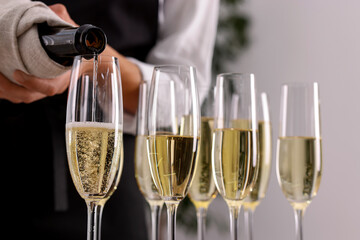 Waiter filling glasses with champagne indoors, closeup