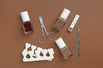 Set of pedicure tools on brown background, flat lay