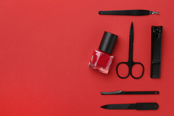 Set of pedicure tools on red background, flat lay. Space for text