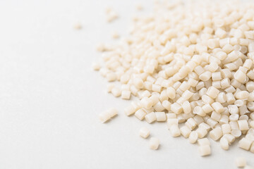Pile of plastic granules on white background, closeup. Space for text