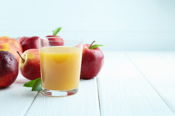 Refreshing apple juice in glass and fruits on white wooden table, closeup. Space for text