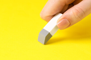 Woman using eraser on yellow background, closeup. Space for text