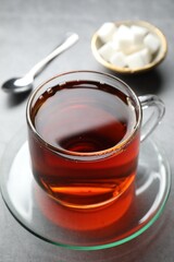 Refreshing black tea in cup on grey table, closeup