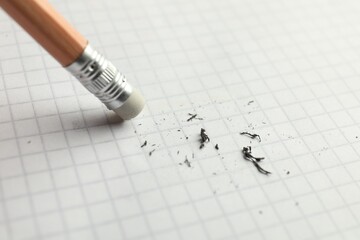 Using pencil with eraser on white sheet of paper, closeup